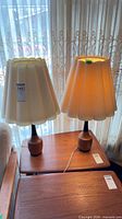 Pair of teak base lamps on table, full view with shades
