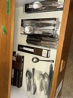Drawer containing multiple Oneida flatware boxes and individually bagged utensils