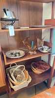 Overall view showing fondue pot, serving pieces, art glass candle holder, wooden bowl and two wicker baskets on shelving
