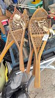 Two pairs of wooden snowshoes showing frames, webbing and bindings
