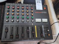Top view of Tascam M-06st mixer showing controls, faders, VU meters and power switch