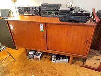 Front view of teak sideboard showing sliding doors, legs, overall form