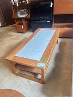 Full view of teak coffee table showing tile inlay and lower shelf