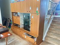 Full view of assembled three-section teak cupboard against wall