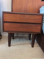 Front view of teak nightstand showing two drawers and tapered legs