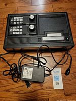 ColecoVision console with two controllers and power adapter displayed on floor