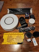 All items laid out including mitre box, LED fixture, round glass cover, fan, candle, casters, chargers, brush, battery monitor