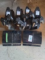 Six PS3 consoles arranged with four controllers on top