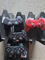 Front view of six PS3 consoles standing vertically with four controllers on top