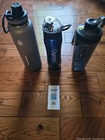 Three water bottles standing side by side on floor
