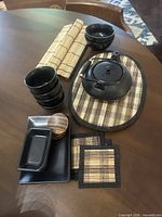 Group view of ceramic teapot, bowls, dishes, wooden coasters, bamboo mats
