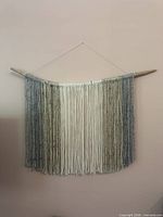 Full view of yarn macrame wall hanging showing gradient colours and driftwood rod