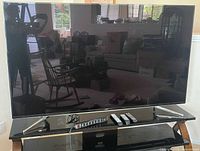 Front view of Samsung 75-inch TV with three remotes on table