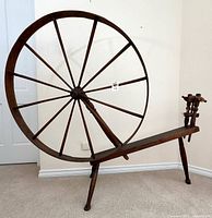 Full view of large twelve-spoke wooden spinning wheel on bench