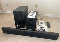 Soundbar, subwoofer, additional black rectangular component, manuals, cables, remote