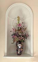 Full view of vase with attached artificial arrangement in alcove