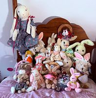 Group shot of all plush bunnies on bed showing variety and sizes