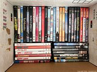 Top view of box showing rows of DVD spines with war and drama titles such as The King’s Speech, Gettysburg, Windtalkers