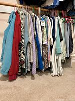 Closet rod showing multiple jackets, sweaters, vests, shirts, pants