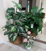 Overall view of both large potted plants in wicker baskets and smaller floral arrangement in front
