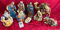 Full view of all 10 Nativity pieces displayed on red fabric