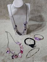 Overview showing two shell necklaces on display and three bracelets
