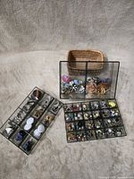Overall view: two sectioned trays, glass display box with assorted earrings, wicker basket
