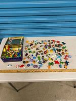 Overall lot showing tin and spread of small toys with ruler for scale