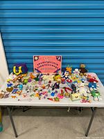 Full table view of entire toy lot showing Ouija board, plushes, figurines and miniatures