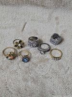 Group shot of all seven rings arranged on fabric surface