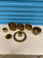 Group view: three pierced brass bowls, brass cup, brass planter on feet, zodiac ring, tealight holder
