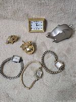 Group shot of all seven items: three wristwatches, acorn box, two elephant figurines, desk clock