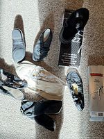 Assorted black jazz shoes and white ballet slippers laid out with two original shoe boxes visible
