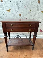 Full view of mahogany end table showing drawers, legs, cane shelf
