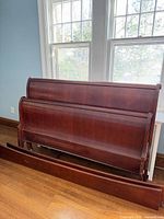 Queen solid cherry sleigh bed components stacked: headboard, footboard, side rails