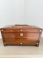 Front view showing rosewood grain, inlay washers, lock escutcheon, bun feet