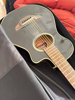 Full view of Yamaha black cutaway acoustic guitar in soft case
