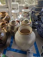 Group of three porcelain vases inside blue tape area