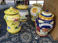 Group shot of four ceramic biscotti jars showing designs and relative sizes
