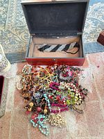 Lot overview showing wooden box and pile of assorted necklaces