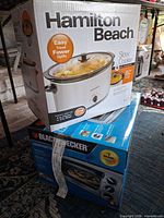 Hamilton Beach slow cooker box stacked on Black+Decker countertop oven box