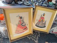 two framed artworks leaning together showing full fronts