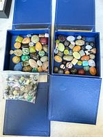 Overview showing two open blue boxes of stones, a third box beneath and a plastic bag of small stones