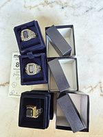 All three rings in velvet display boxes with outer sleeves visible
