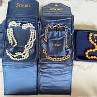 Three open Stauer cases showing all necklaces