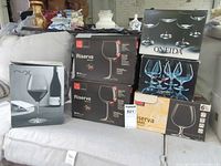Five boxed sets of stemware stacked on sofa