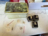 Lot overview showing tin, bagged charms and pin, three boxed thimbles
