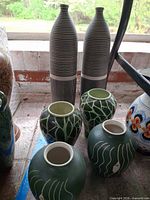 Six vases: two tall striped bottle vases and four globular vases with leaf and face motifs