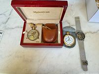 Full view showing all three watches: Majestron boxed pocket watch, Rail Master pocket watch, Grenen wristwatch