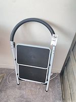 Stool folded showing overall design, metal frame, black steps